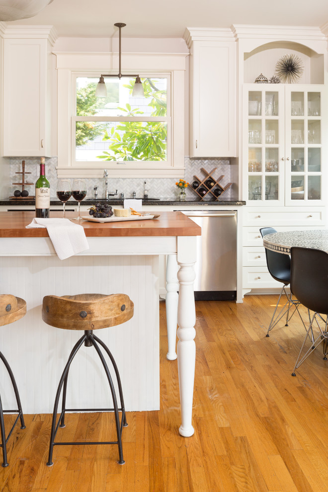 Open concept kitchen - large l-shaped light wood floor open concept kitchen idea in Seattle with flat-panel cabinets, white cabinets, wood countertops, gray backsplash, stainless steel appliances and an island