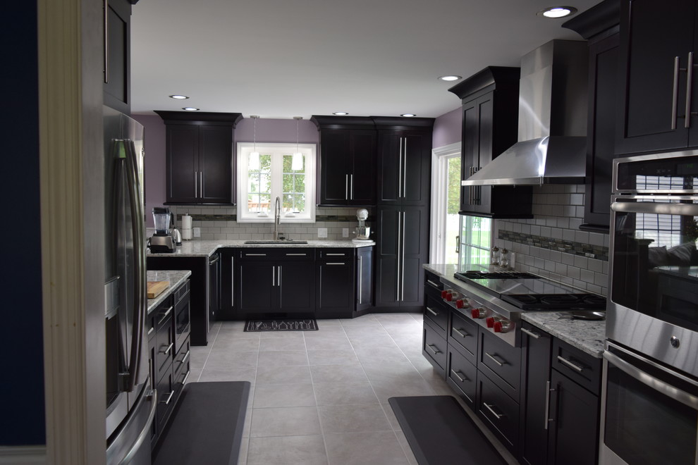 Inspiration for a transitional ceramic tile kitchen remodel with an undermount sink, shaker cabinets, black cabinets, quartz countertops, gray backsplash, subway tile backsplash and stainless steel appliances