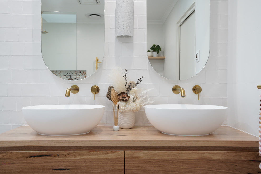 Modelo de cuarto de baño principal, único y flotante escandinavo de tamaño medio con puertas de armario de madera oscura, bañera exenta, ducha abierta, baldosas y/o azulejos blancos y suelo de baldosas de cerámica