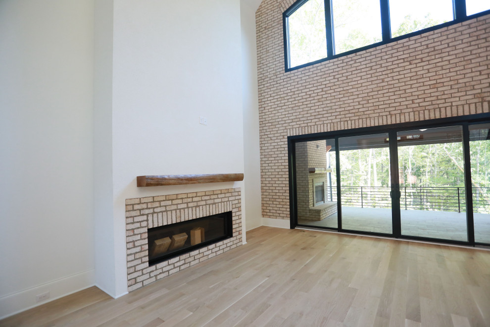 Пример оригинального дизайна: большая открытая гостиная комната в стиле модернизм с белыми стенами, паркетным полом среднего тона, горизонтальным камином, фасадом камина из кирпича, сводчатым потолком и кирпичными стенами