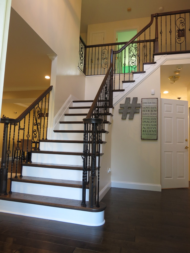 Large transitional galley dark wood floor and brown floor staircase photo with a double-bowl sink, raised-panel cabinets, white cabinets, granite countertops, white backsplash, porcelain backsplash, stainless steel appliances and an island