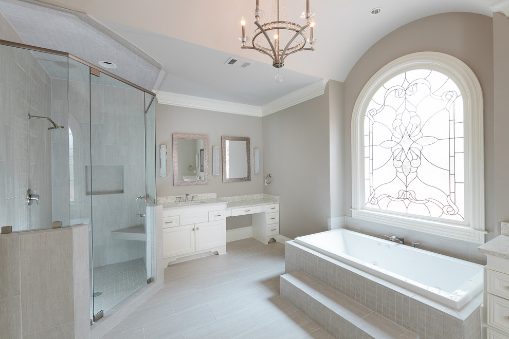 This is an example of a large transitional master bathroom in Atlanta with raised-panel cabinets, white cabinets, a drop-in tub, a corner shower, a two-piece toilet, gray tile, ceramic tile, grey walls, ceramic floors, an undermount sink and engineered quartz benchtops.