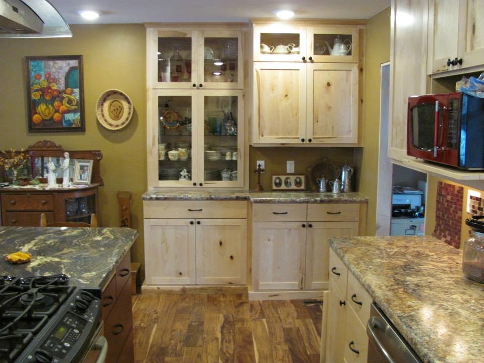 Example of a mid-sized mountain style l-shaped medium tone wood floor and brown floor eat-in kitchen design with a double-bowl sink, shaker cabinets, light wood cabinets, limestone countertops, stainless steel appliances and an island