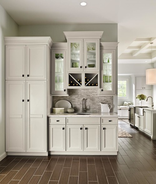 Sophisticated beverage station with light gray shaker RTA cabinets, glass-front uppers, X-shaped wine rack, mosaic backsplash, and tall pantry towers.