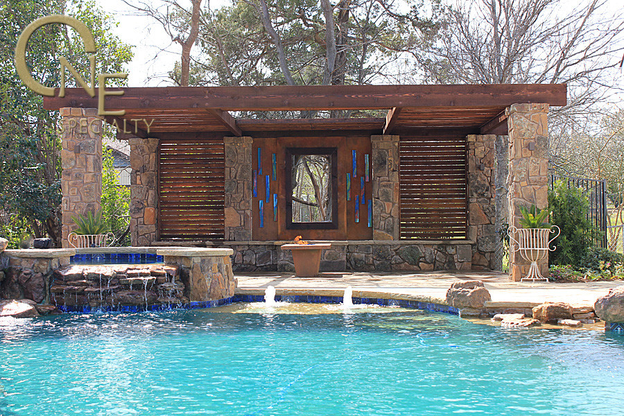 Photo of a mid-sized eclectic backyard custom-shaped infinity pool in Austin with a water feature and natural stone pavers.