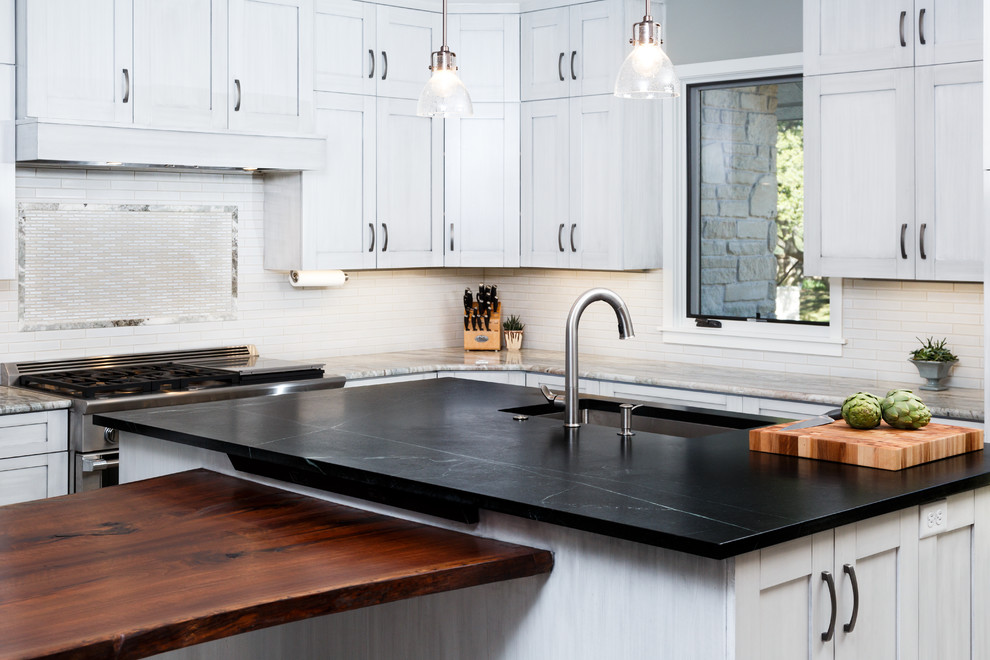 Example of a large transitional l-shaped porcelain tile eat-in kitchen design in Austin with a single-bowl sink, shaker cabinets, gray cabinets, soapstone countertops, white backsplash, ceramic backsplash, stainless steel appliances and an island