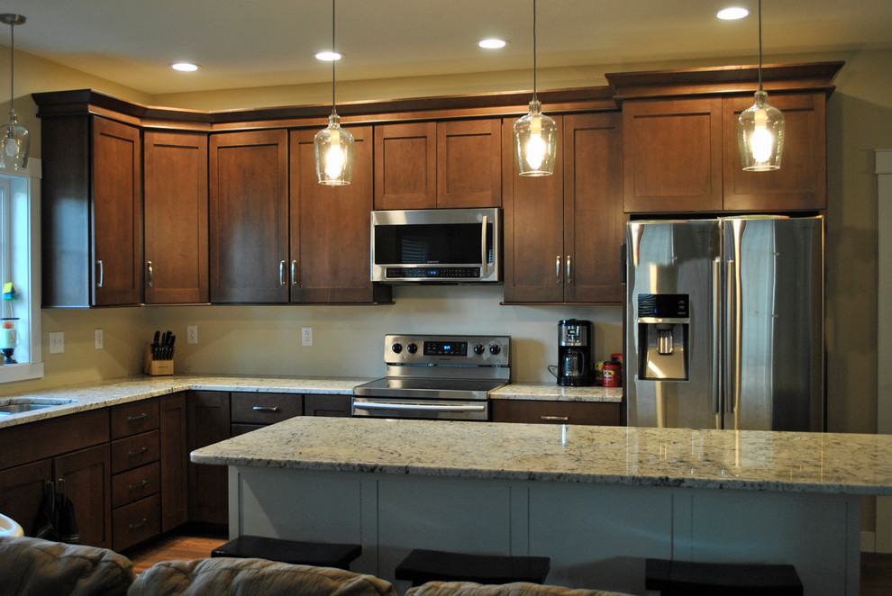 Inspiration for a brown floor kitchen remodel with brown cabinets, stainless steel appliances, an island and beige countertops