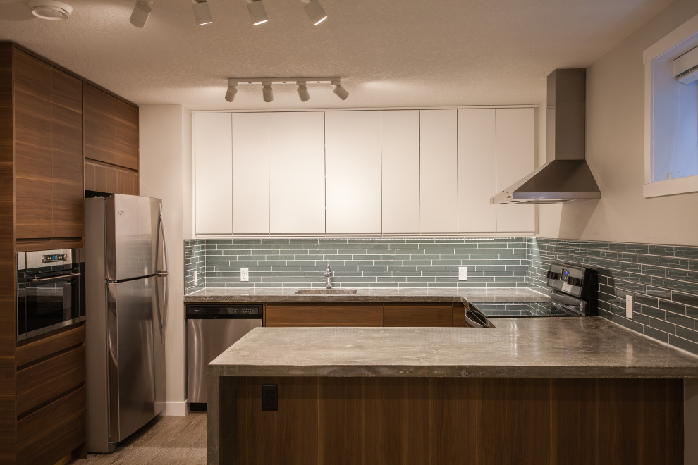 Photo of a mid-sized contemporary u-shaped separate kitchen in Calgary with an undermount sink, flat-panel cabinets, brown cabinets, concrete benchtops, blue splashback, glass tile splashback, stainless steel appliances, vinyl floors, a peninsula, grey floor and grey benchtop.