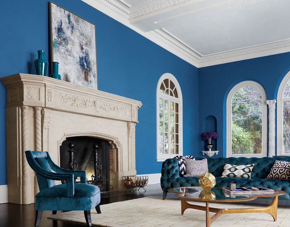 This is an example of a large eclectic formal open concept living room in Los Angeles with blue walls, dark hardwood floors, a standard fireplace, a stone fireplace surround, no tv and brown floor.