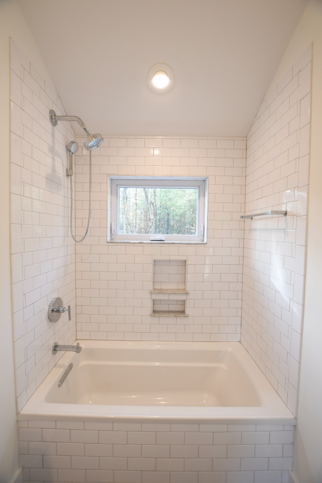 Photo of a mid-sized country kids bathroom in New York with flat-panel cabinets, white cabinets, a drop-in tub, a shower/bathtub combo, a one-piece toilet, white tile, ceramic tile, white walls, medium hardwood floors, an integrated sink, solid surface benchtops, brown floor, an open shower, white benchtops, a single vanity, a freestanding vanity and vaulted.