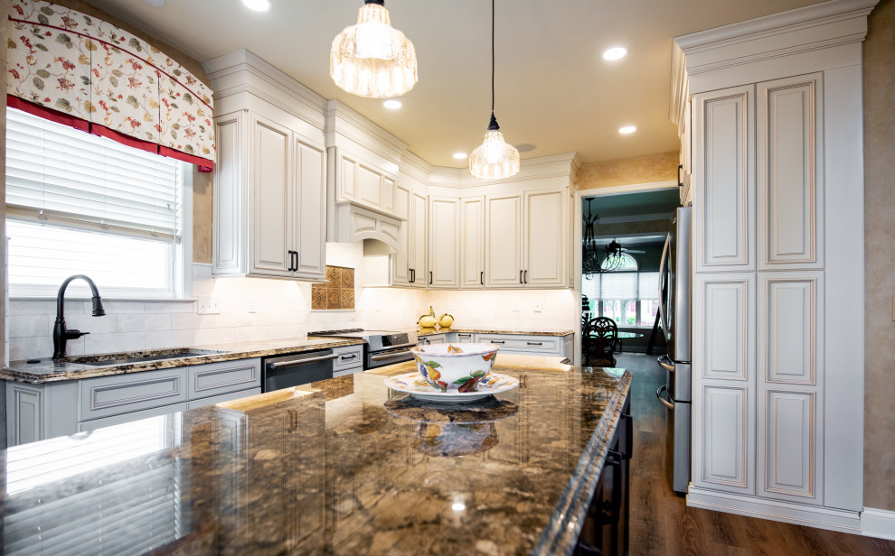 Photo of a mid-sized transitional l-shaped eat-in kitchen in Philadelphia with an undermount sink, raised-panel cabinets, white cabinets, granite benchtops, white splashback, marble splashback, stainless steel appliances, vinyl floors, with island, brown floor and brown benchtop.