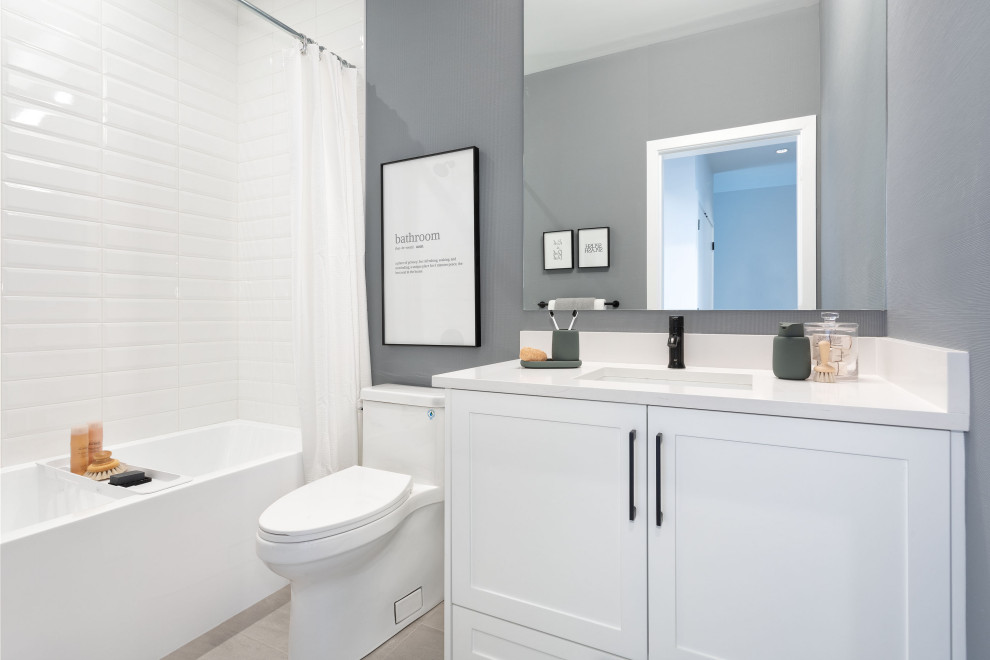 This is an example of a small scandinavian kids bathroom in Vancouver with flat-panel cabinets, white cabinets, an alcove tub, an alcove shower, a one-piece toilet, white tile, ceramic tile, blue walls, porcelain floors, an undermount sink, quartzite benchtops, beige floor, white benchtops, a single vanity, a built-in vanity and wallpaper.