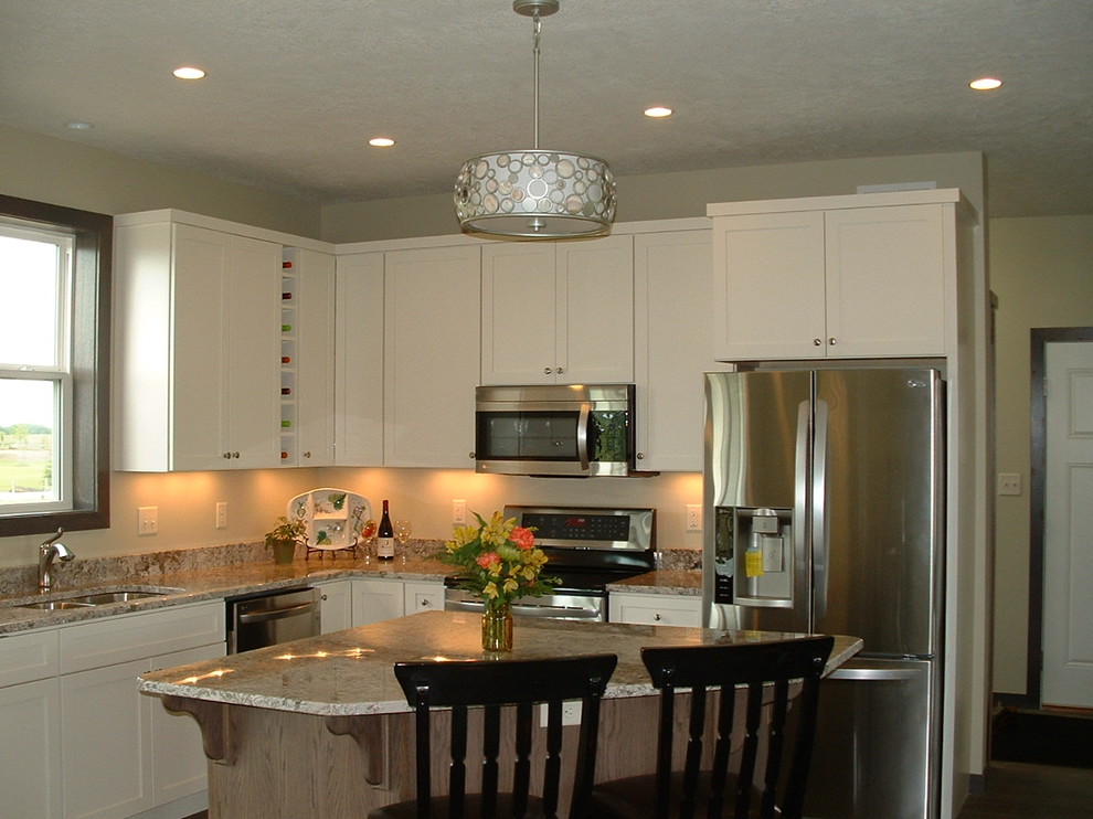 This is an example of a traditional eat-in kitchen in Other with an undermount sink, flat-panel cabinets, white cabinets, granite benchtops, stainless steel appliances and with island.