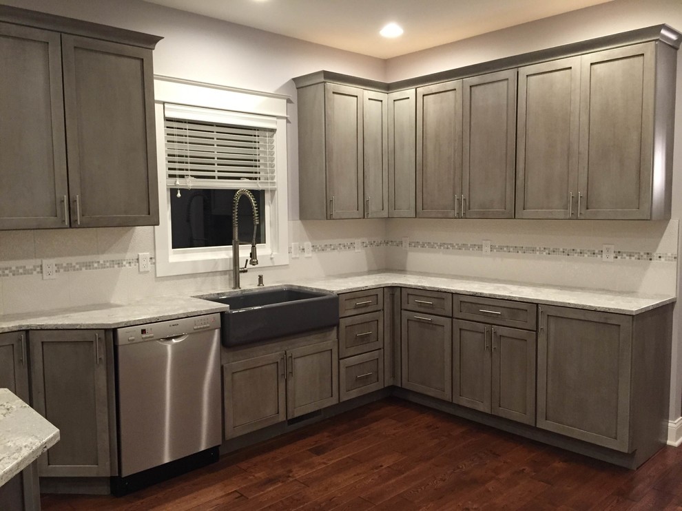 Large transitional l-shaped medium tone wood floor eat-in kitchen photo in Grand Rapids with a farmhouse sink, shaker cabinets, gray cabinets, quartz countertops, white backsplash, porcelain backsplash, stainless steel appliances and an island