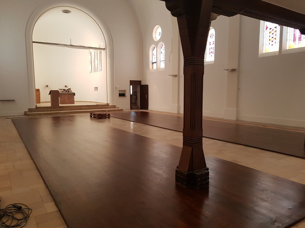 Wohnzimmer in grau-weiß mit weißer Wandfarbe, gebeiztem Holzboden, braunem Boden, gewölbter Decke, Wandpaneelen und Rundbogen in Berlin