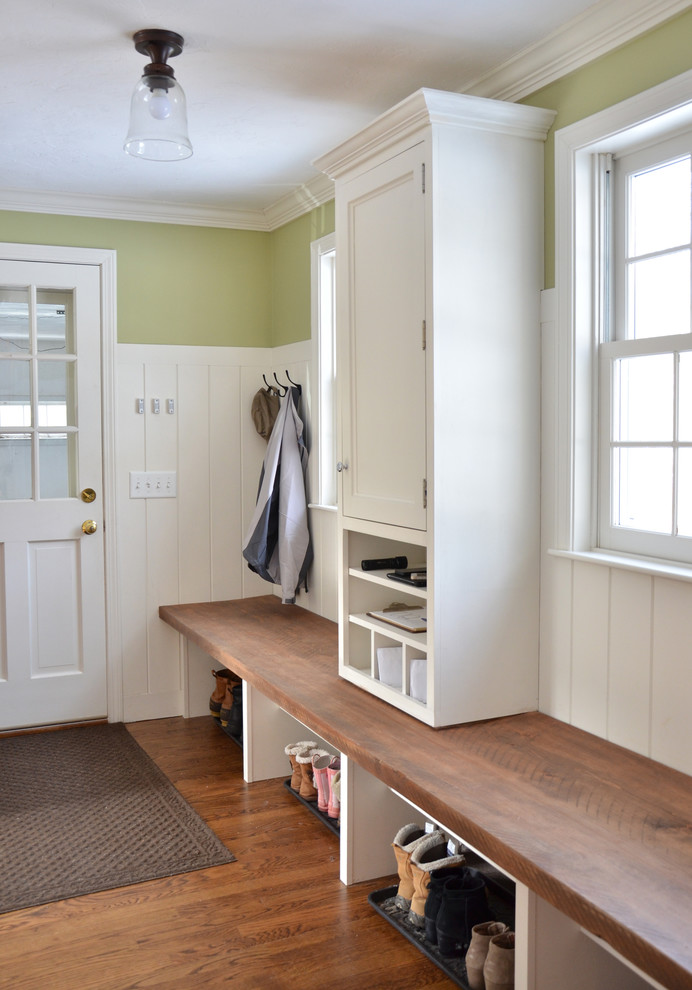 This is an example of a traditional mudroom in Boston with green walls and medium hardwood floors.