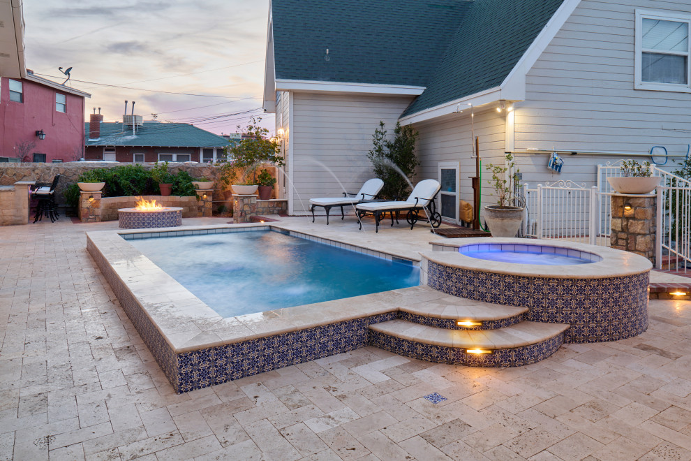Ejemplo de piscina con fuente tradicional rectangular en patio trasero con adoquines de piedra natural