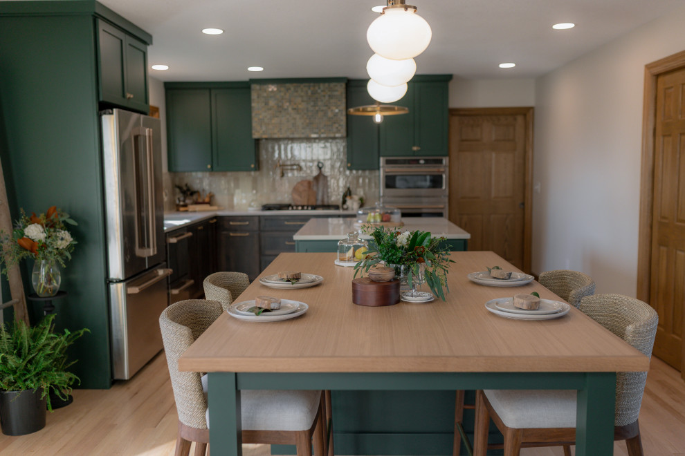 Example of a mid-sized transitional l-shaped light wood floor and brown floor eat-in kitchen design with an undermount sink, recessed-panel cabinets, green cabinets, quartz countertops, beige backsplash, terra-cotta backsplash, stainless steel appliances, two islands and beige countertops