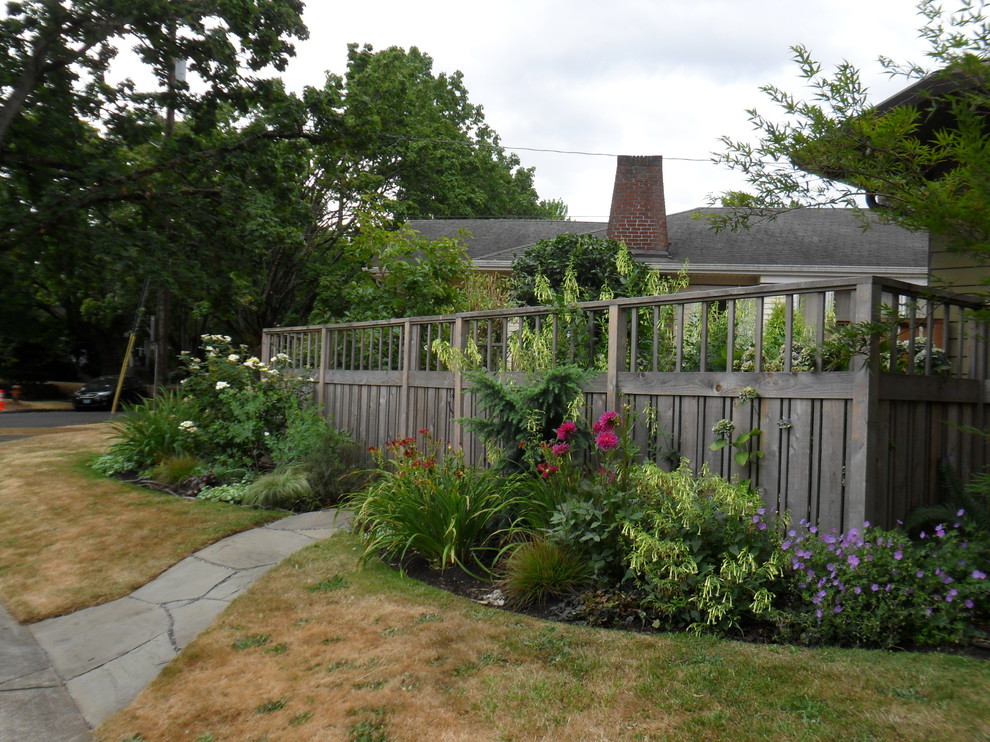Small eclectic front yard full sun garden in Portland with natural stone pavers for summer.