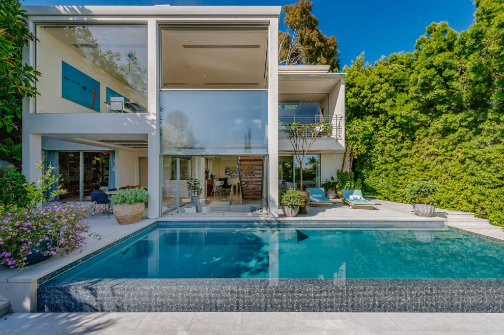 This is an example of a large modern backyard rectangular infinity pool in Los Angeles with a hot tub.