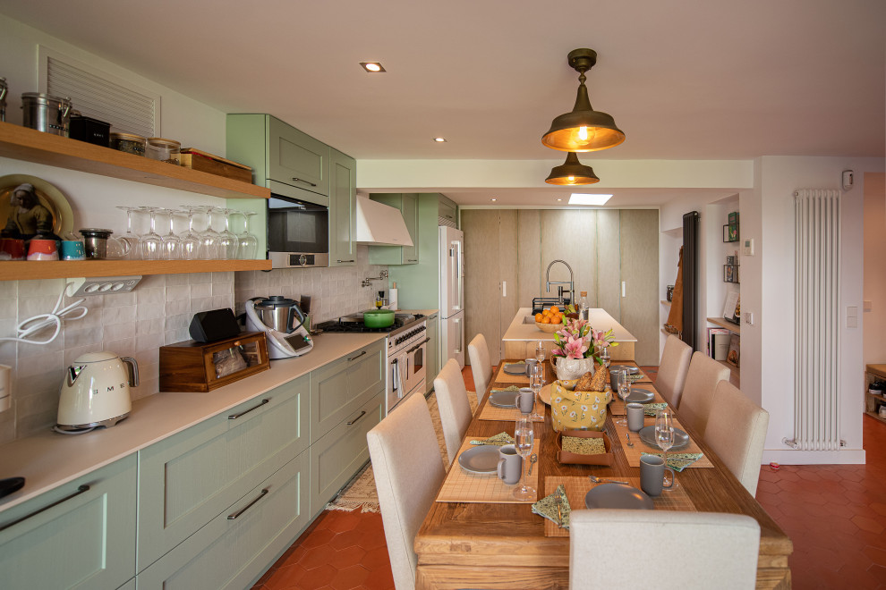 Exempel på ett stort modernt beige linjärt beige kök och matrum, med en undermonterad diskho, luckor med upphöjd panel, gröna skåp, bänkskiva i kvarts, vitt stänkskydd, stänkskydd i keramik, rostfria vitvaror, klinkergolv i terrakotta, en köksö och rött golv