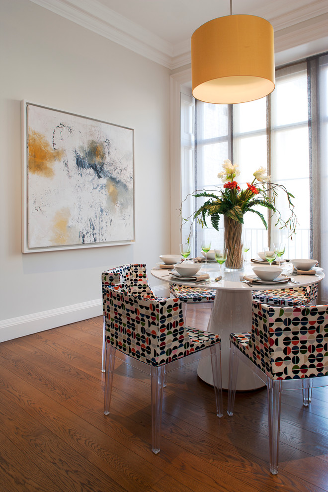 This is an example of a contemporary dining room in London with white walls and medium hardwood floors.