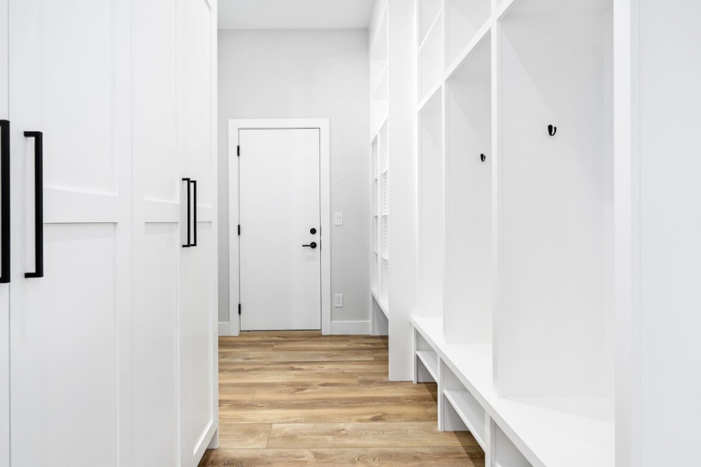 Small country mudroom in Calgary with white walls, light hardwood floors and brown floor.