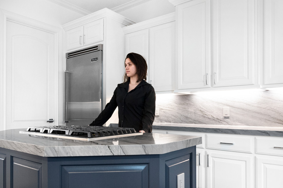 Eat-in kitchen - mid-sized transitional galley medium tone wood floor and gray floor eat-in kitchen idea in Houston with a farmhouse sink, raised-panel cabinets, blue cabinets, quartzite countertops, gray backsplash, stone slab backsplash, stainless steel appliances, an island and gray countertops