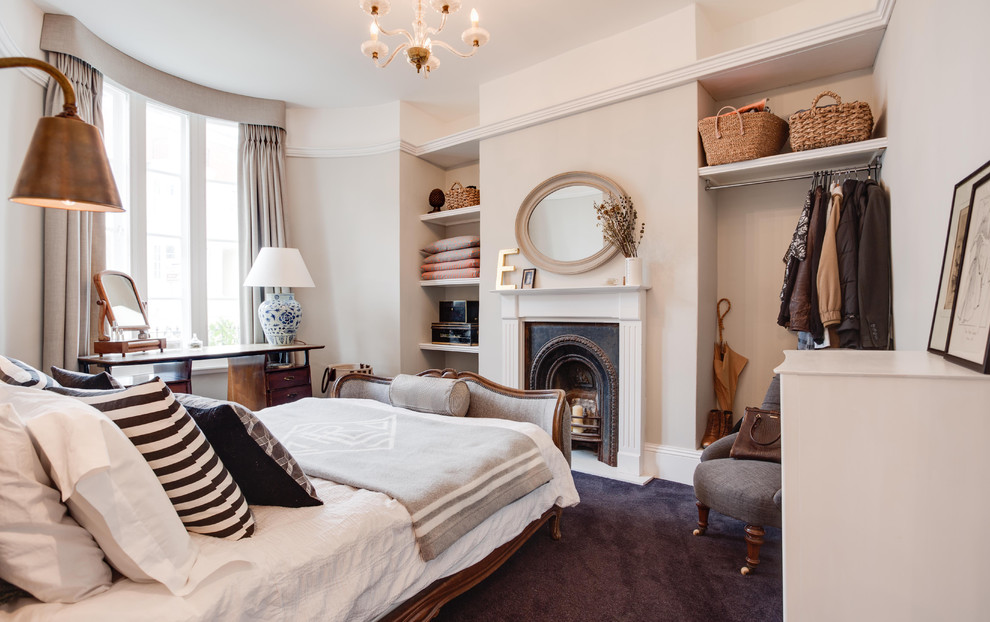 Inspiration for a small eclectic master bedroom in Hampshire with grey walls, carpet, a standard fireplace and a wood fireplace surround.