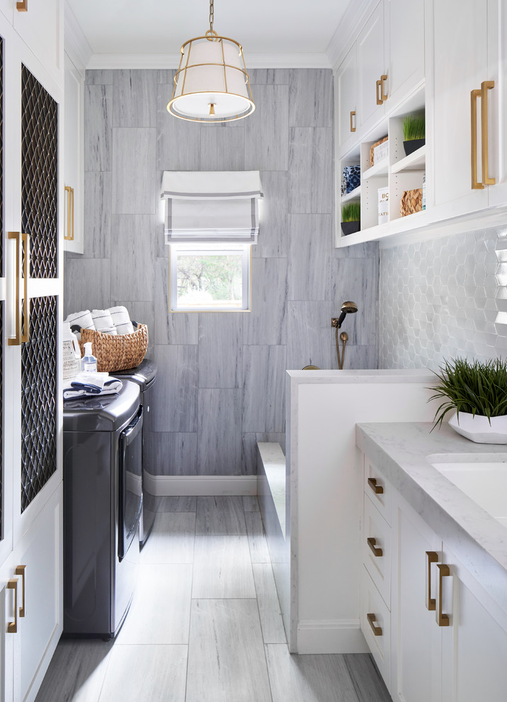 Inspiration for a mid-sized transitional galley dedicated laundry room in Austin with an undermount sink, shaker cabinets, white cabinets, a side-by-side washer and dryer, grey floor, grey benchtop, quartz benchtops, blue walls and porcelain floors.