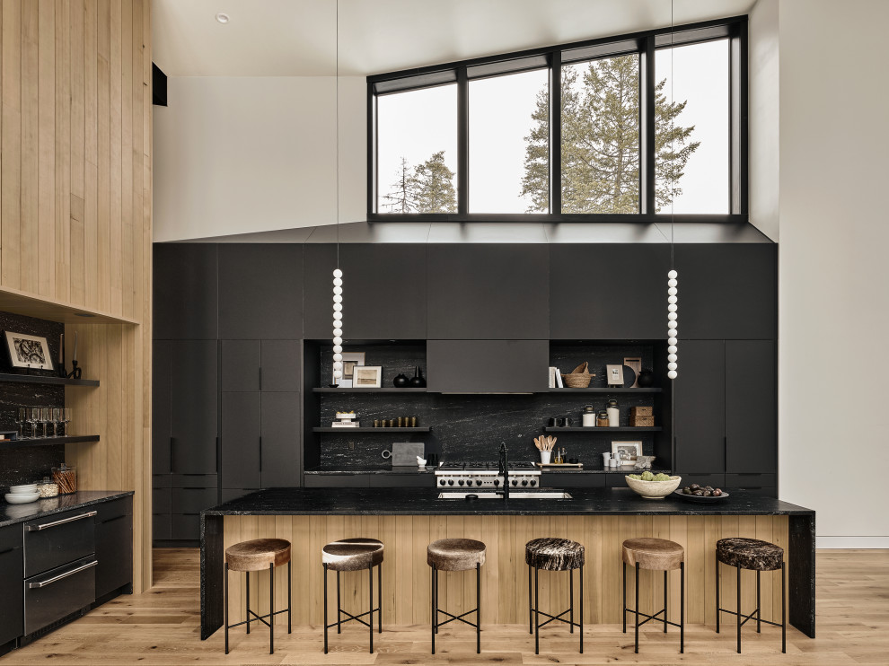 Inspiration for a modern single-wall light wood floor and vaulted ceiling open concept kitchen remodel in Phoenix with a single-bowl sink, black cabinets, granite countertops, black backsplash, granite backsplash, stainless steel appliances, an island and black countertops