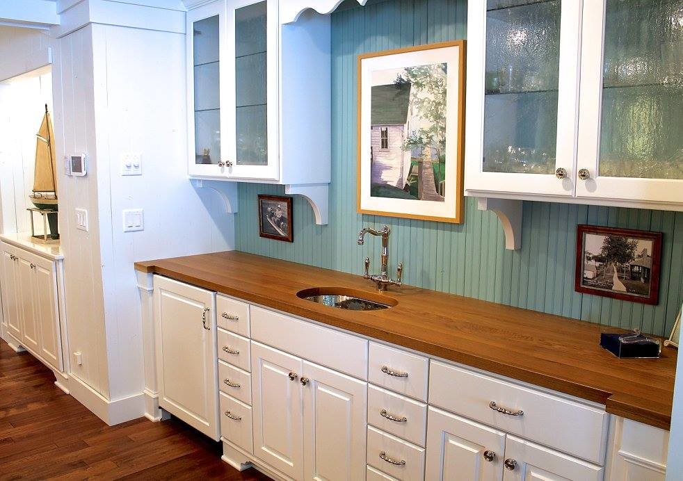 Mid-sized country single-wall wet bar in Other with an undermount sink, glass-front cabinets, white cabinets, wood benchtops, green splashback, timber splashback, medium hardwood floors and brown floor.