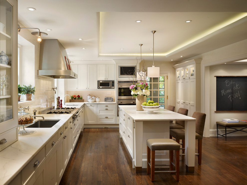 Photo of a traditional l-shaped kitchen in Philadelphia with an undermount sink, recessed-panel cabinets, white cabinets, white splashback, subway tile splashback and stainless steel appliances.