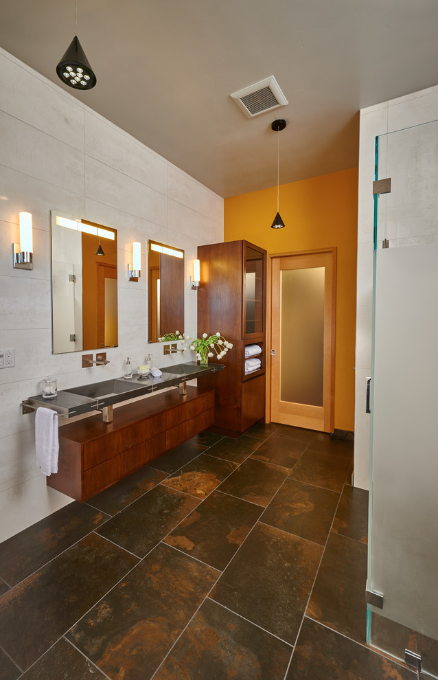 Mid-sized modern master bathroom in San Francisco with an integrated sink, recessed-panel cabinets, medium wood cabinets, a curbless shower, a wall-mount toilet, gray tile, ceramic tile, multi-coloured walls, ceramic floors, a freestanding tub, stainless steel benchtops, multi-coloured floor and a hinged shower door.