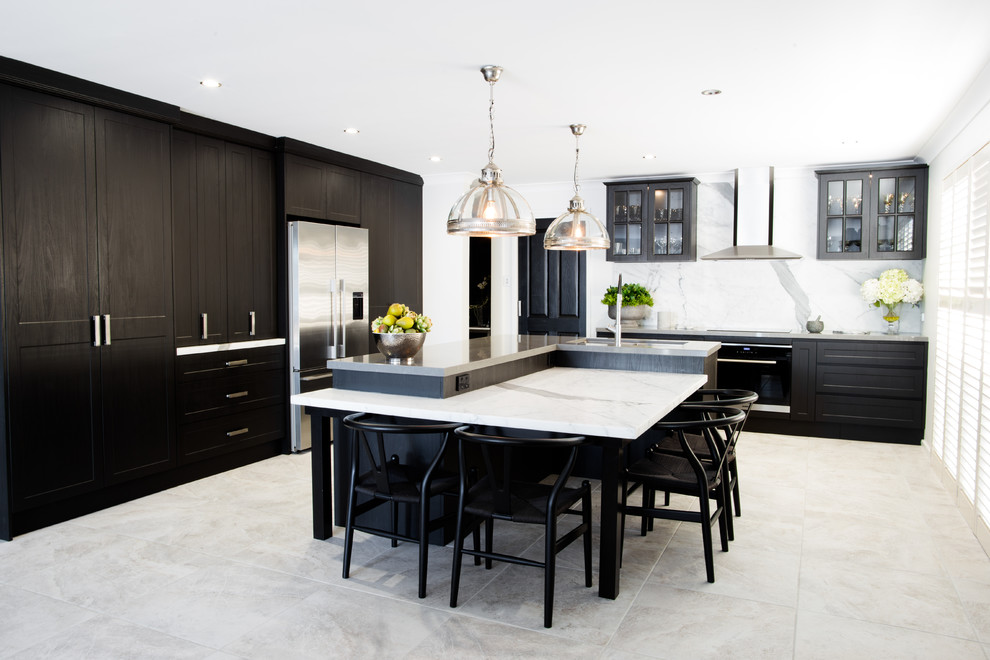 Photo of a small transitional l-shaped eat-in kitchen in Central Coast with a double-bowl sink, black cabinets, quartz benchtops, white splashback, stone slab splashback, stainless steel appliances, ceramic floors, with island, grey floor, shaker cabinets and white benchtop.