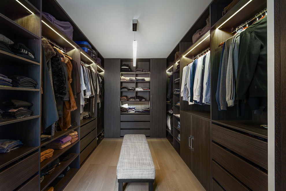 This is an example of a large contemporary gender-neutral walk-in wardrobe in Paris with open cabinets, dark wood cabinets, light hardwood floors and beige floor.