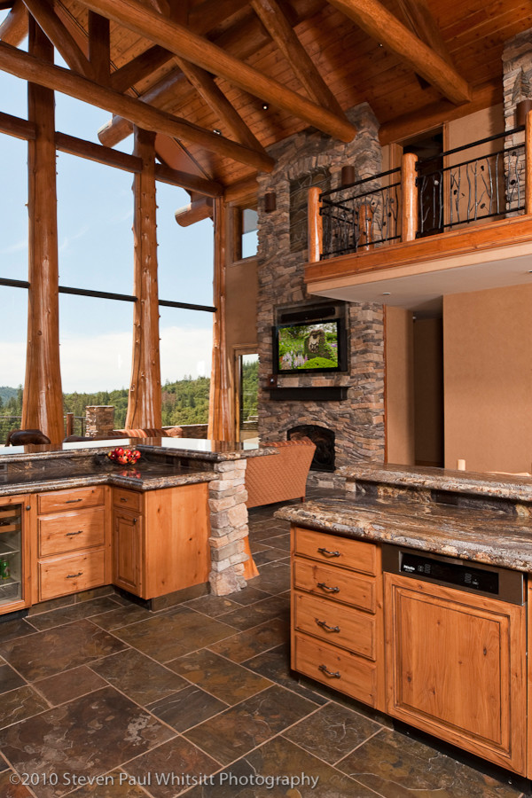 Open concept kitchen - huge rustic u-shaped slate floor open concept kitchen idea with an undermount sink, raised-panel cabinets, distressed cabinets, granite countertops, multicolored backsplash, stone slab backsplash, stainless steel appliances and a peninsula