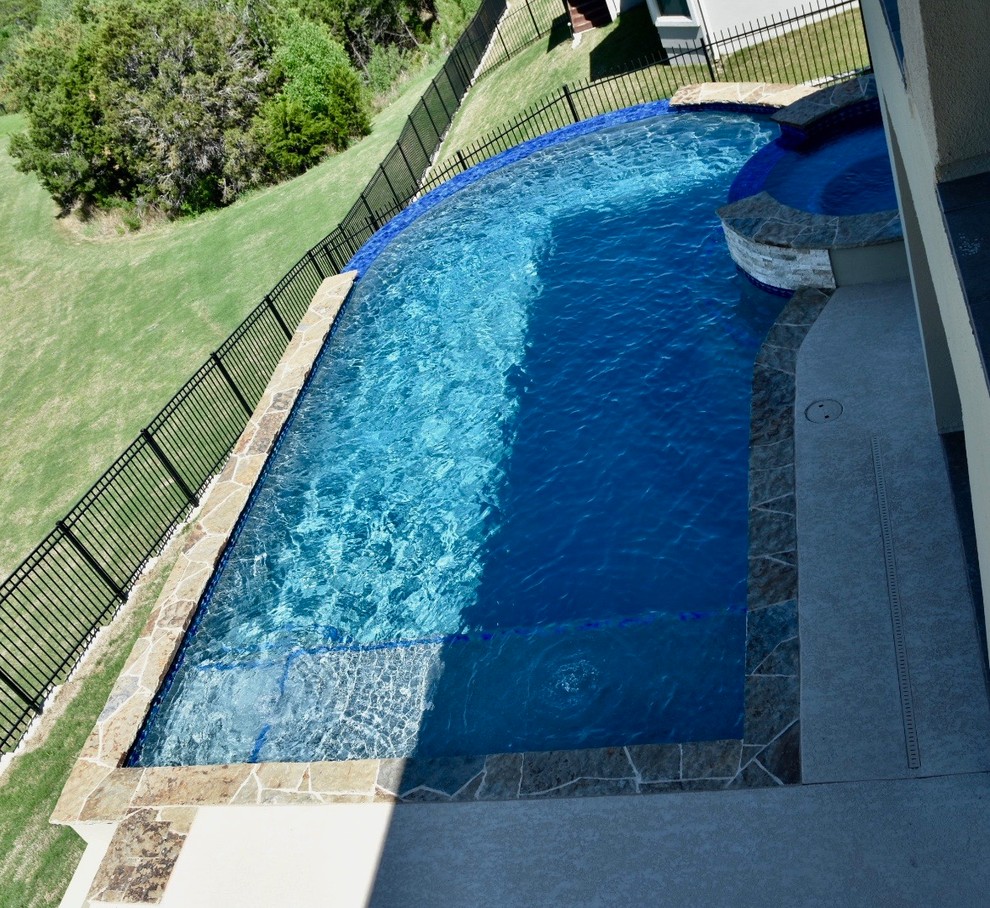 Mid-sized transitional backyard concrete and custom-shaped infinity hot tub photo in Austin
