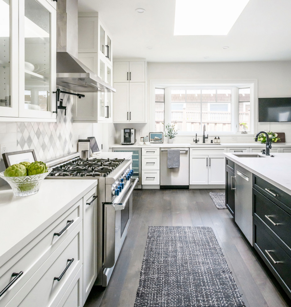 Contemporary open plan kitchen in San Francisco with an undermount sink, shaker cabinets, white cabinets, quartz benchtops, multi-coloured splashback, stainless steel appliances, dark hardwood floors, with island, brown floor and white benchtop.