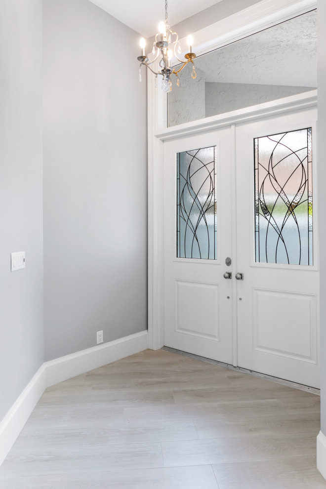 Inredning av en klassisk mycket stor entré, med grå väggar, klinkergolv i porslin, en dubbeldörr, en vit dörr och grått golv