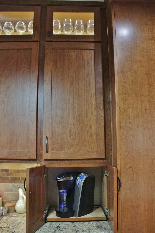 Example of a mid-sized transitional galley ceramic tile enclosed kitchen design with an undermount sink, shaker cabinets, medium tone wood cabinets, quartz countertops, beige backsplash, stone tile backsplash, stainless steel appliances and a peninsula