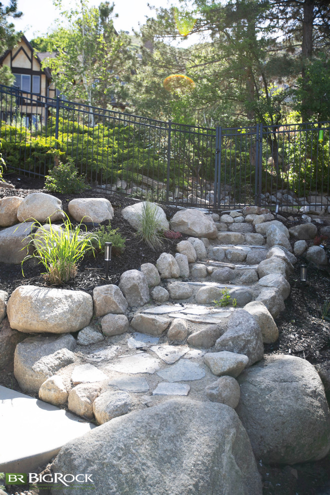 Esempio di un giardino minimal con sassi e rocce, un pendio, una collina o una riva, sassi di fiume e recinzione in metallo