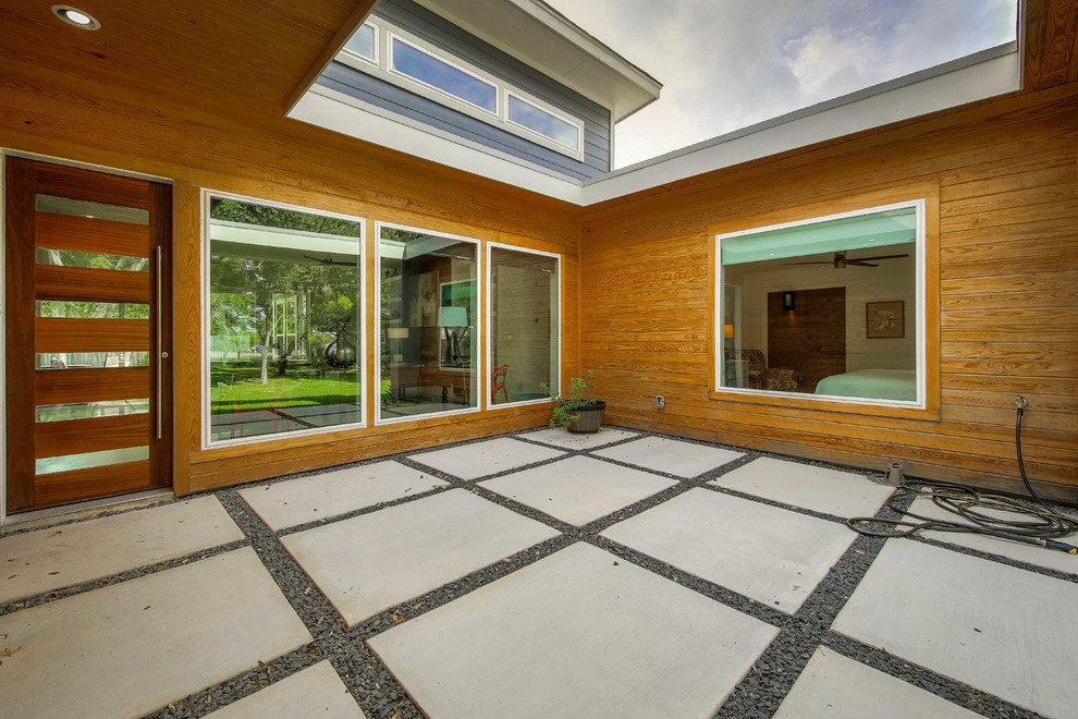 Mid-sized mid-century modern concrete floor and gray floor front door photo in Austin with gray walls and a medium wood front door
