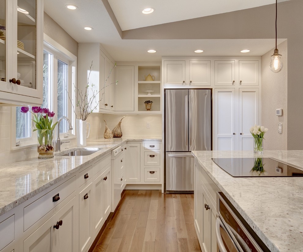 Design ideas for a transitional l-shaped kitchen in Seattle with an undermount sink, shaker cabinets, white cabinets, stainless steel appliances, with island and window splashback.