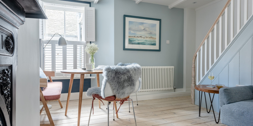 Foto de salón abierto nórdico pequeño con paredes azules, suelo de madera clara, todas las chimeneas, marco de chimenea de metal, televisor independiente y vigas vistas
