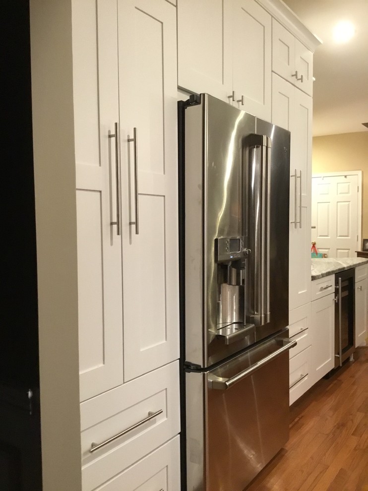 Example of a mid-sized transitional u-shaped medium tone wood floor and brown floor open concept kitchen design in DC Metro with an undermount sink, shaker cabinets, white cabinets, granite countertops, white backsplash, subway tile backsplash, stainless steel appliances, an island and gray countertops