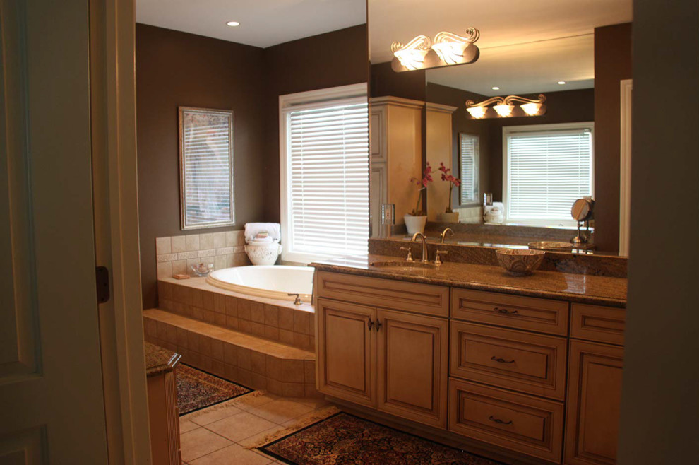 Photo of a traditional bathroom in Cleveland with an undermount sink, distressed cabinets, granite benchtops, a drop-in tub and white tile.