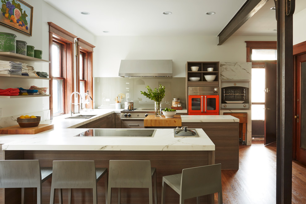 This is an example of a contemporary u-shaped kitchen in Chicago with a double-bowl sink, open cabinets, grey splashback, glass sheet splashback, coloured appliances, medium hardwood floors, multiple islands and orange floor.