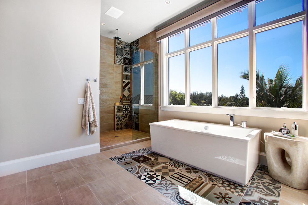Photo of a tropical master bathroom in Other with a freestanding tub, a corner shower, brown tile, gray tile, beige walls and an open shower.