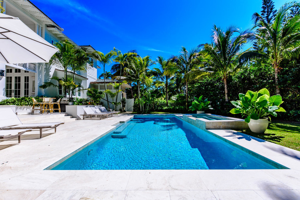 This is an example of a large backyard rectangular natural pool in Miami with a water feature and tile.